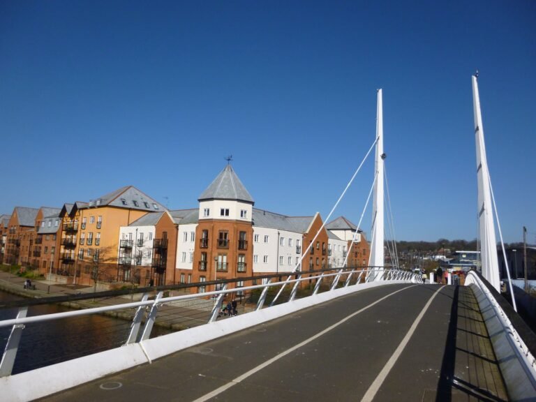 Modern apartment blocks beside the River Wensum in Norwich, seen from a white cable-stayed footbridge