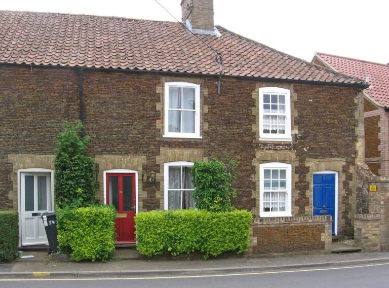 Row of brown carrstone cottages with red brick window surrounds on Paradise Road, Downham Market